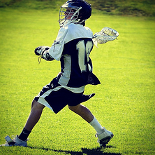 Teenager playing lacrosse wearing a SquadLocker uniform