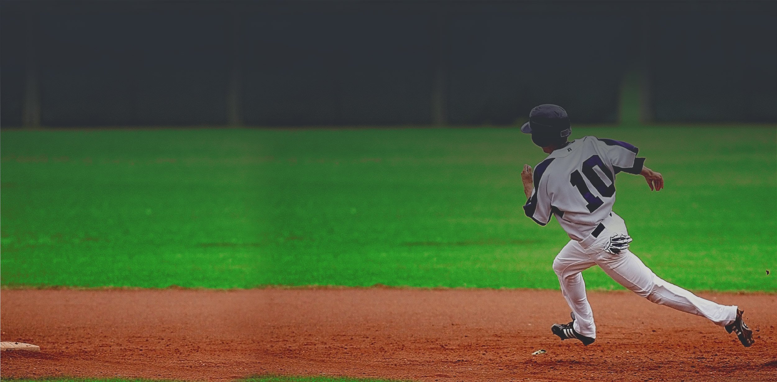 Baseball player running around bases in baseball uniform